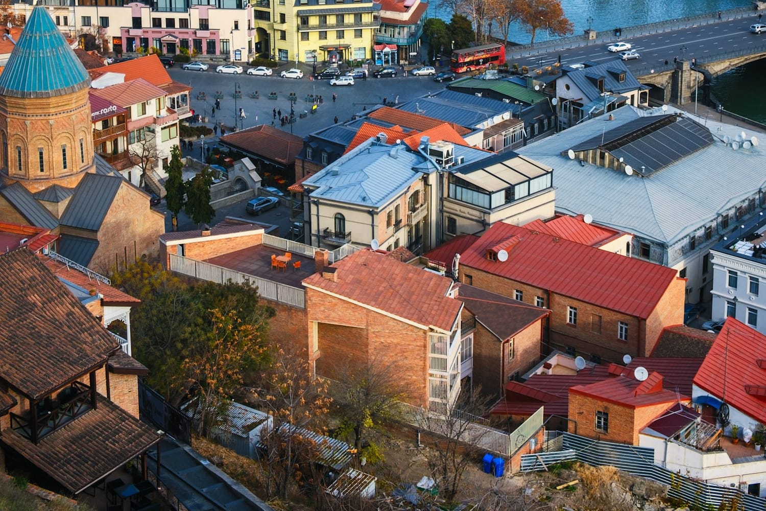 Aerial view of Tbilisi with the Mtkvari river, the Bridge of Peace and autumn trees
