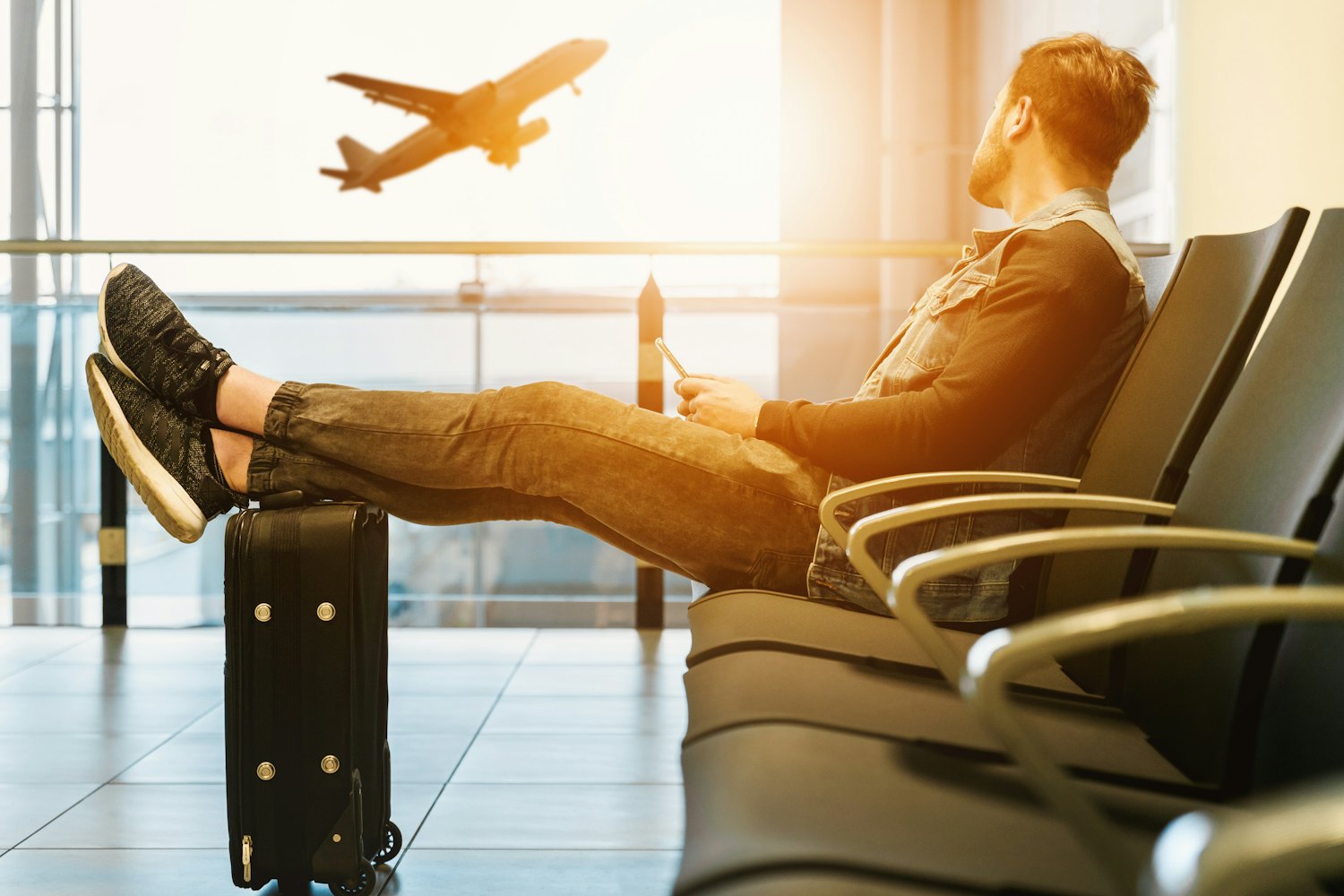 Viaggiatore che riposa in aeroporto mentre un aereo decolla