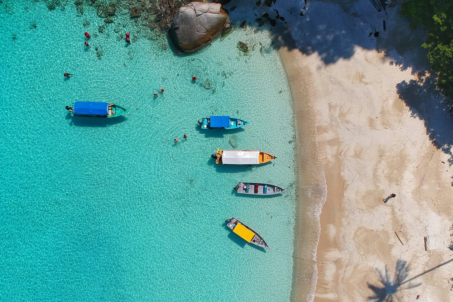 Vista aerea di piccole barche in acqua turchese accanto a una spiaggia tropicale
