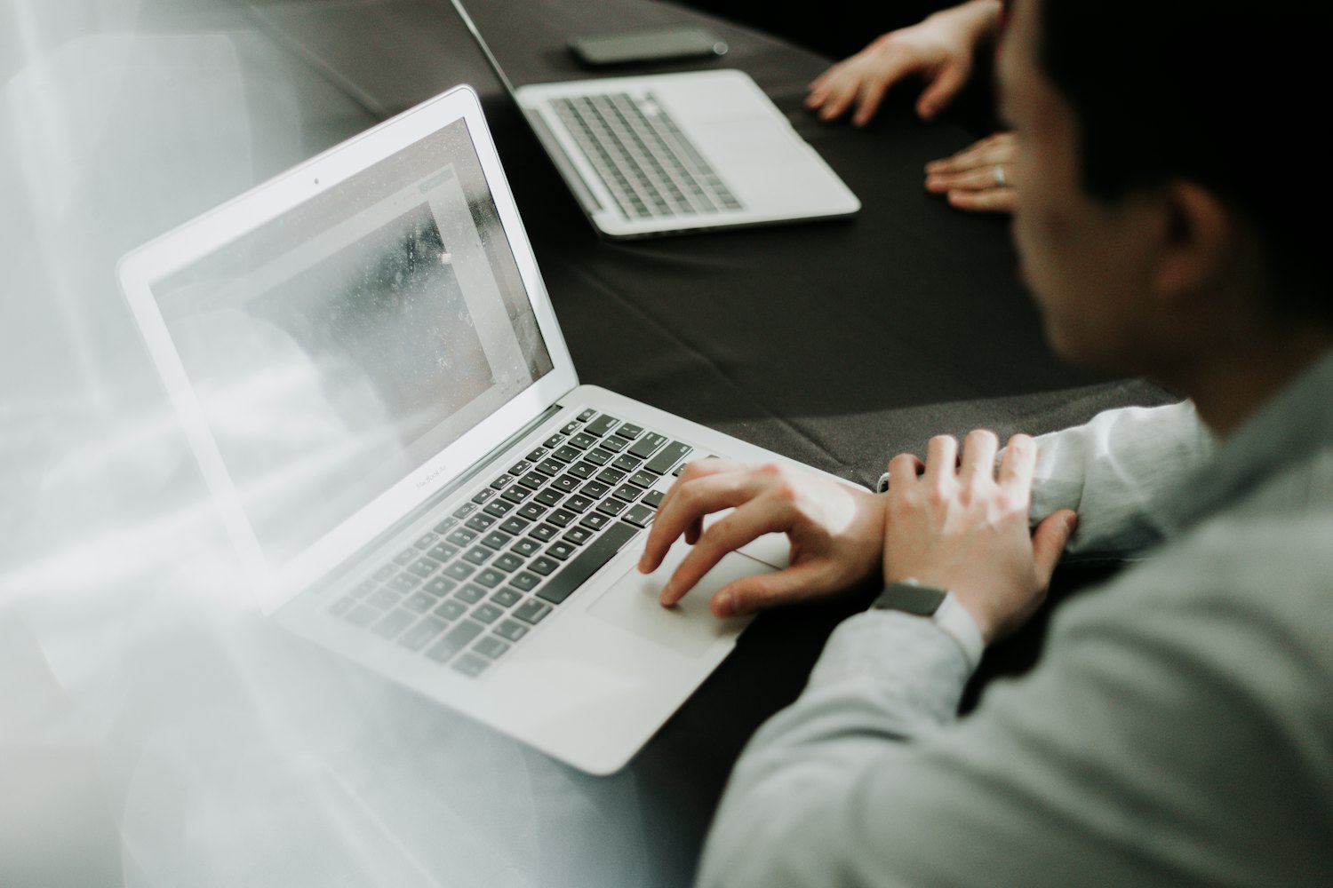 Person working on a laptop at a dark desk