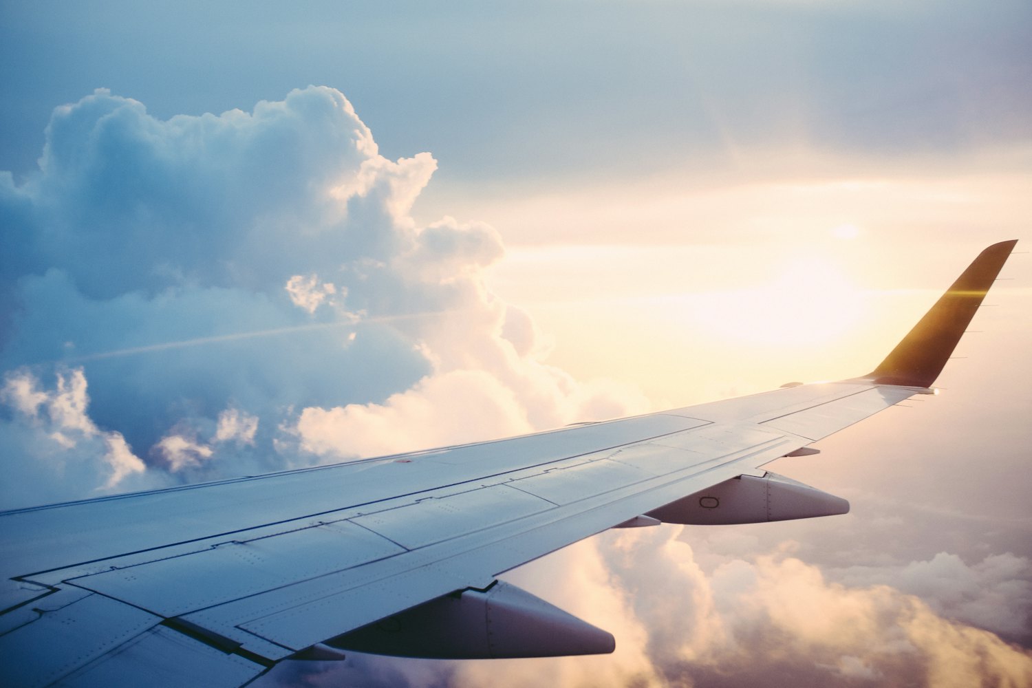 An aircraft wing above the clouds in warm evening light