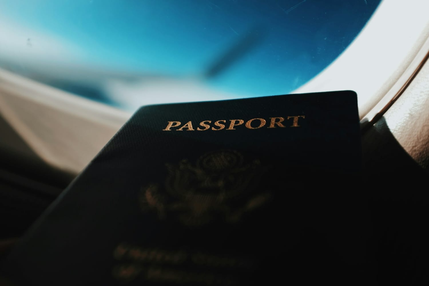 A passport held up beside an aircraft window