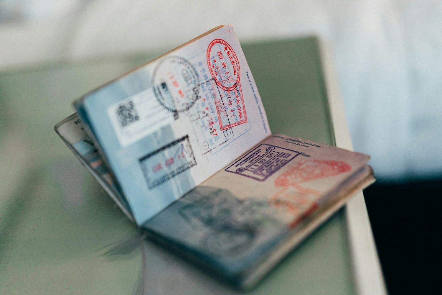 An open passport full of entry stamps resting on a table