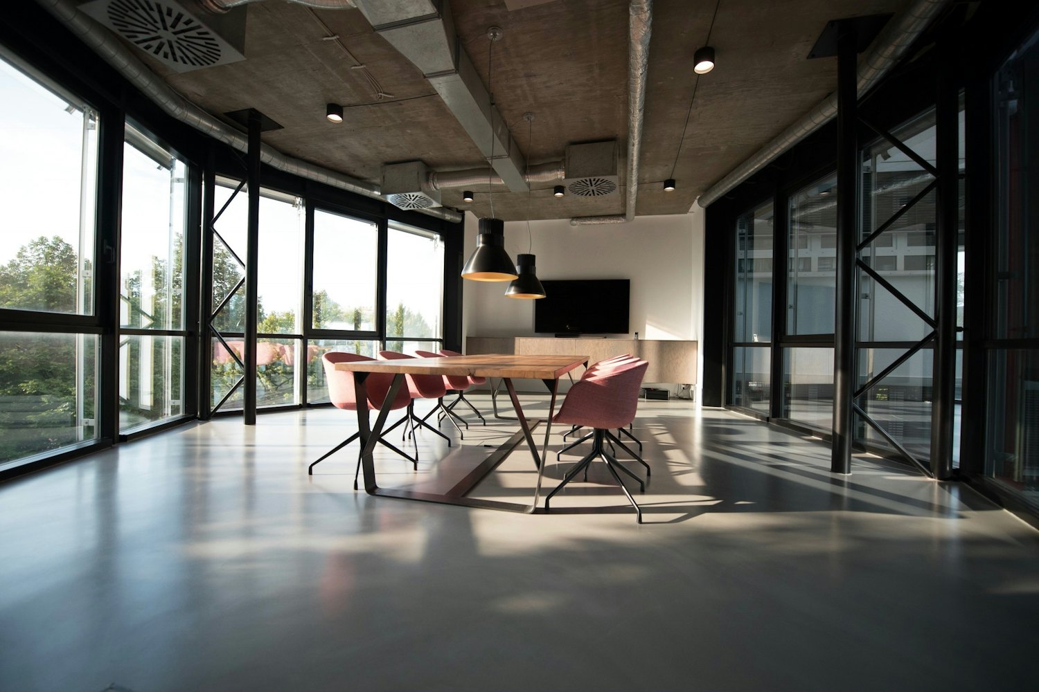 An empty modern office with a long meeting table and floor-to-ceiling windows