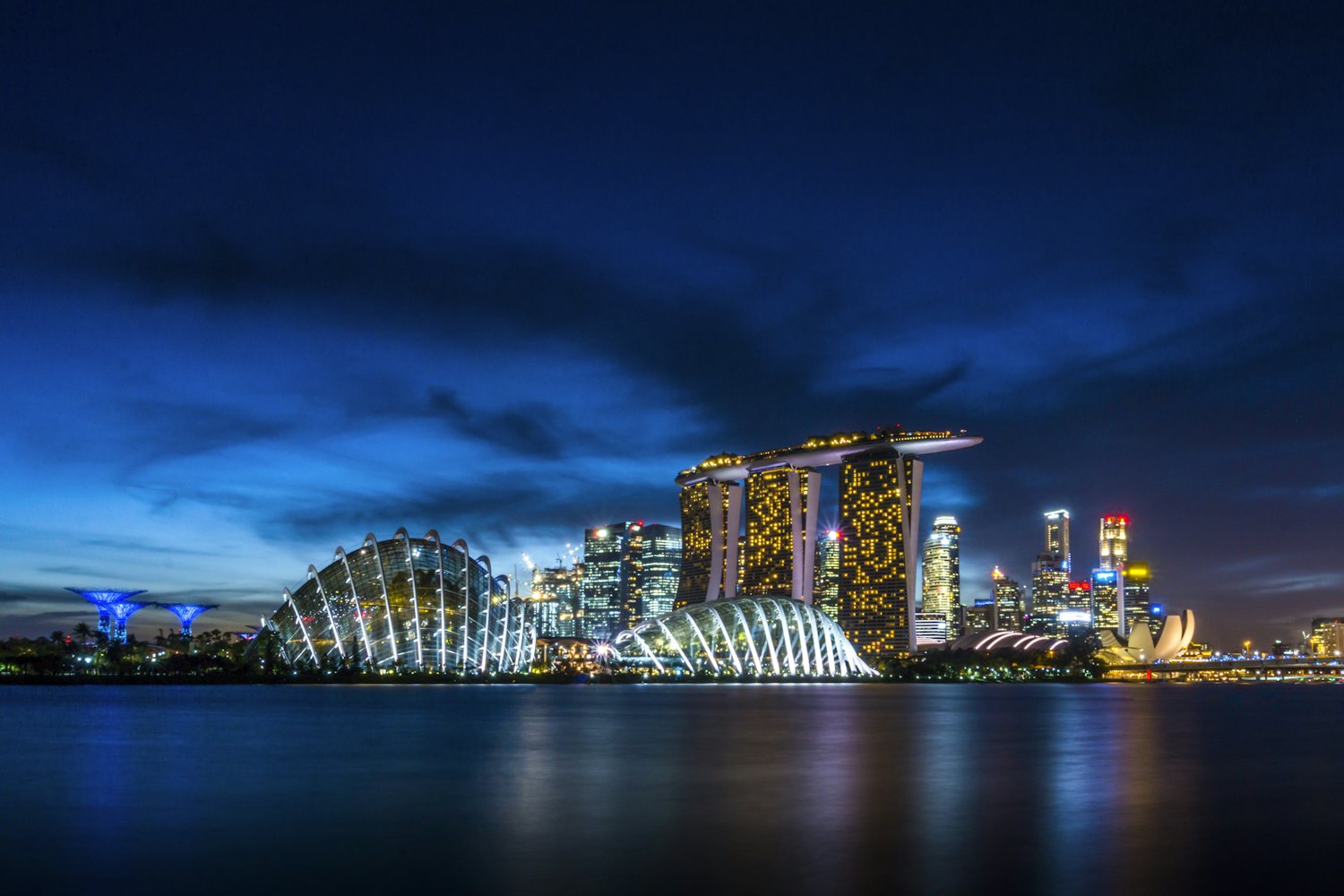 Le cupole di Gardens by the Bay e il Marina Bay Sands riflessi nell'acqua di notte