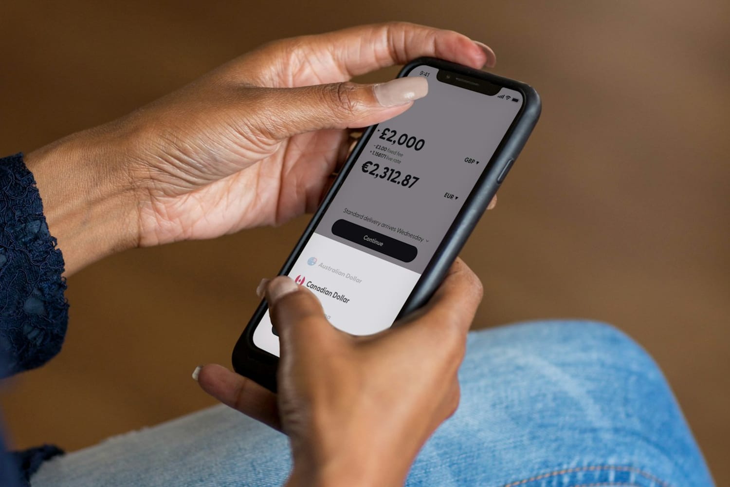 Mani che tengono uno smartphone con saldi in sterline ed euro