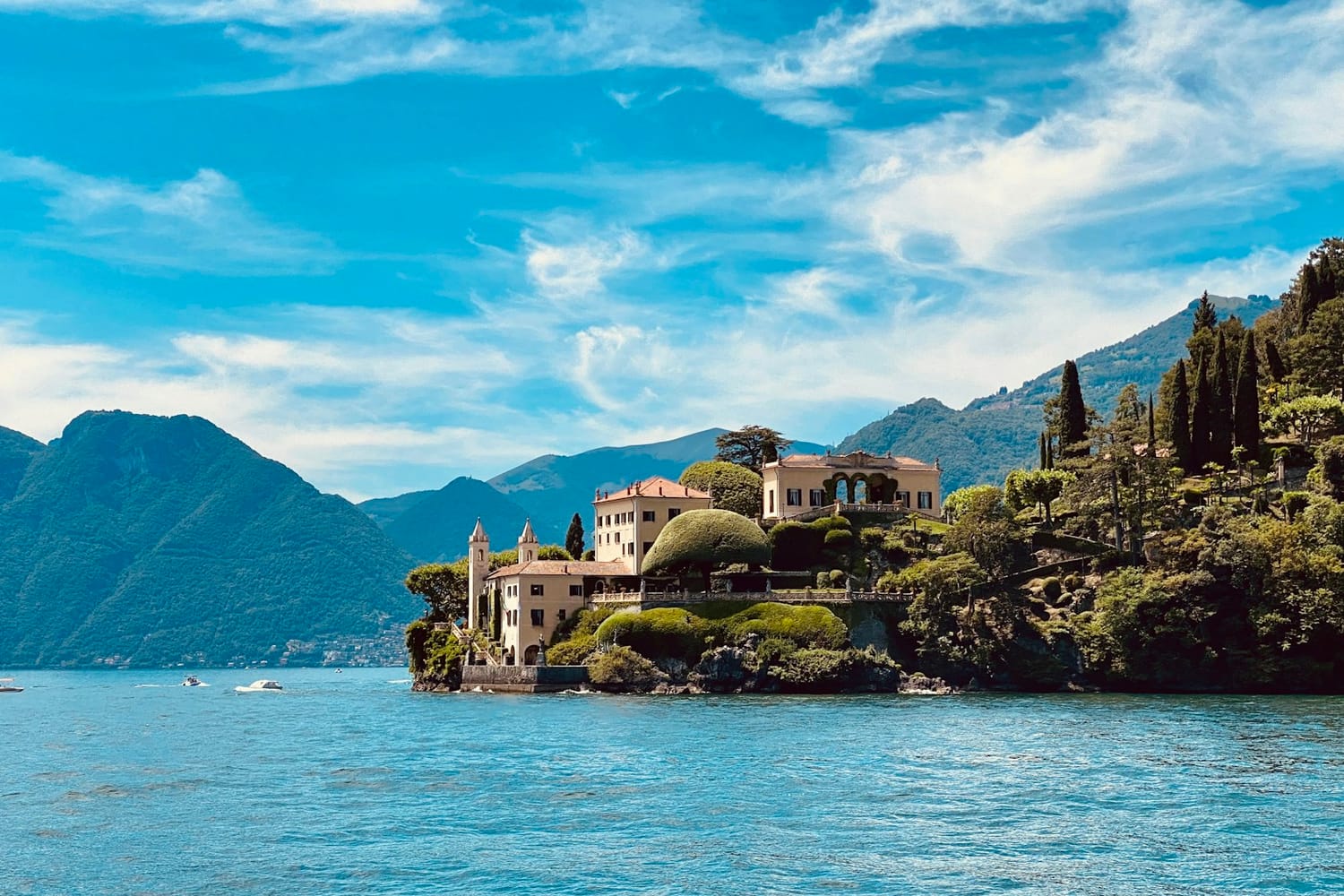 A lakeside villa with gardens on Lake Como, Italy, under a blue sky