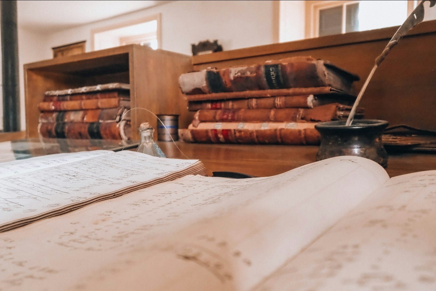 Libros de contabilidad antiguos, un libro de registro abierto y una pluma sobre un escritorio de madera