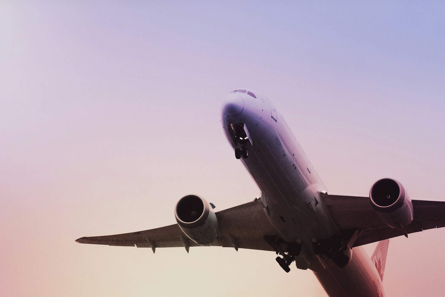 Passenger jet climbing after takeoff against a pastel sky