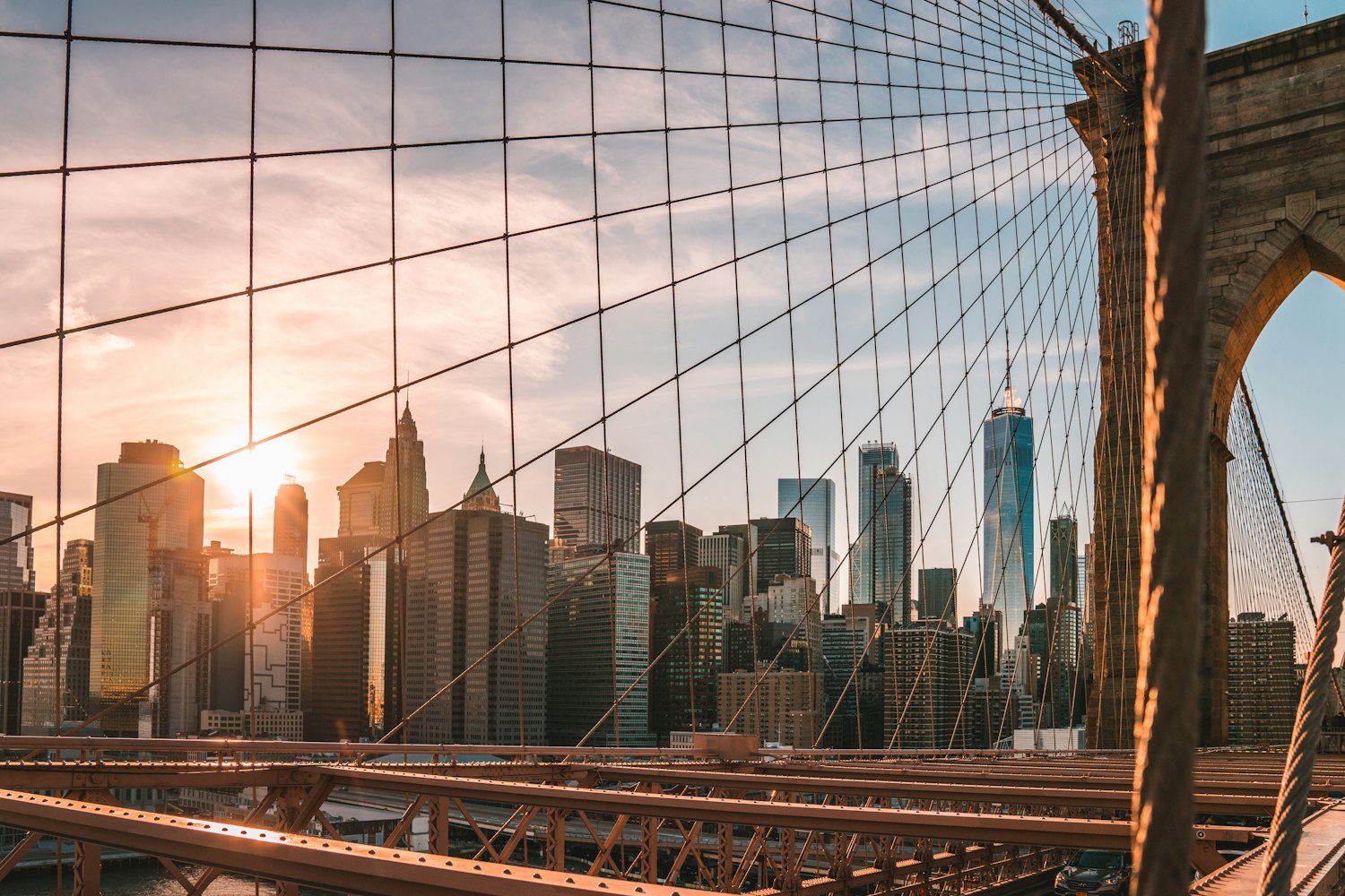 Manhattan towers seen through the cables of the Brooklyn Bridge at sunset