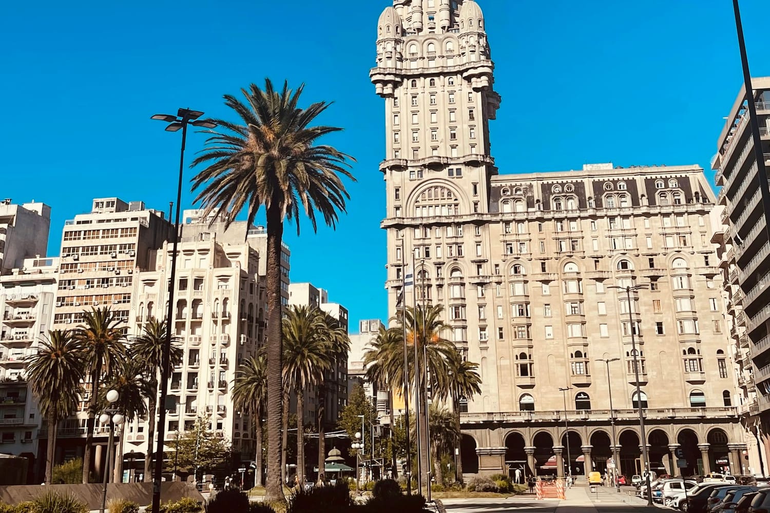 The tower of the Palacio Salvo against a blue sky in Montevideo, with palm trees