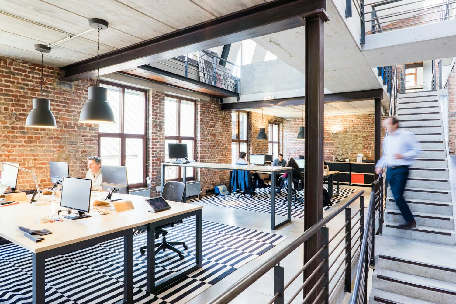 An open-plan office in a converted loft with people working at desks