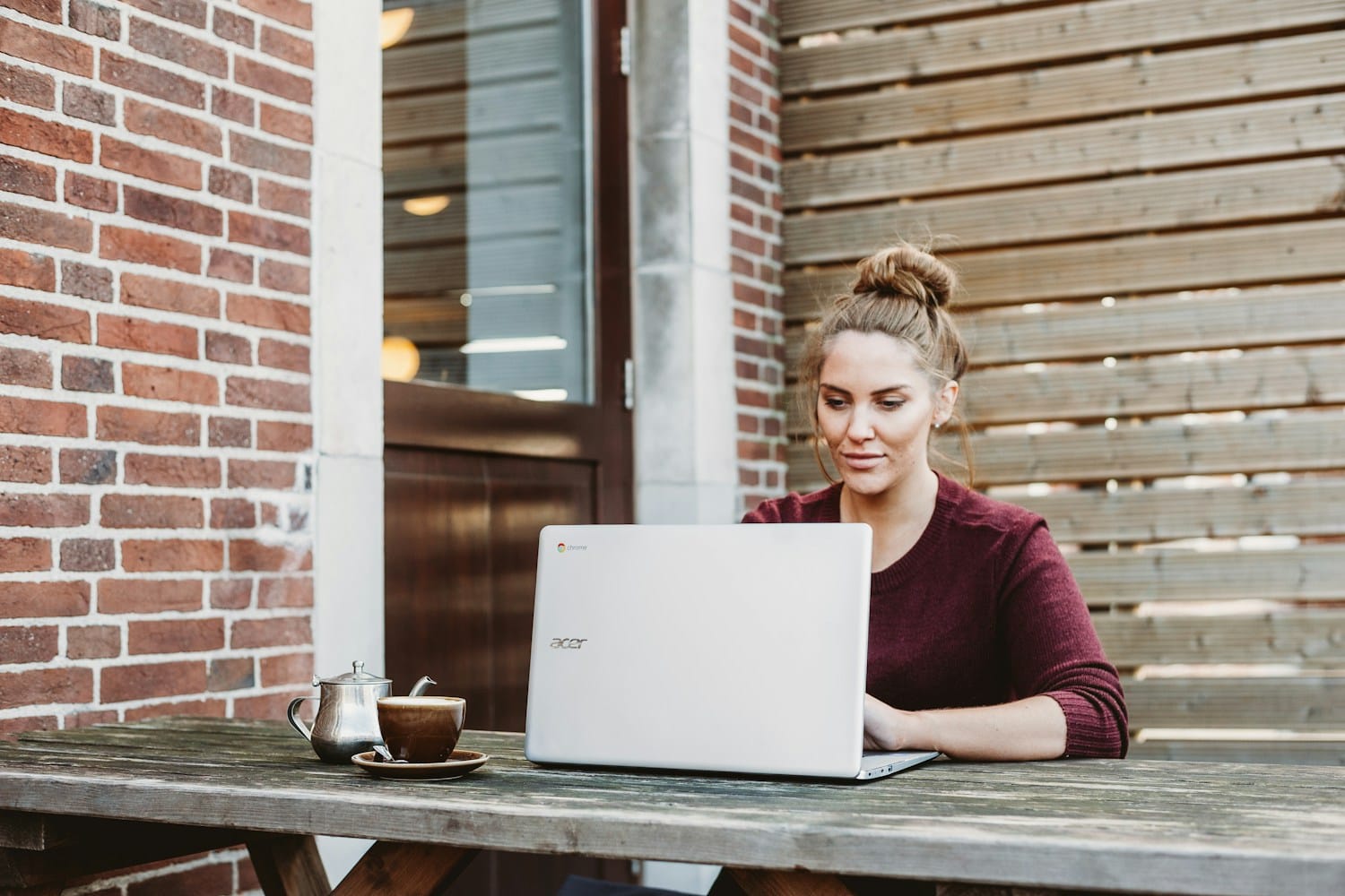A woman working on a laptop at an outdoor café table