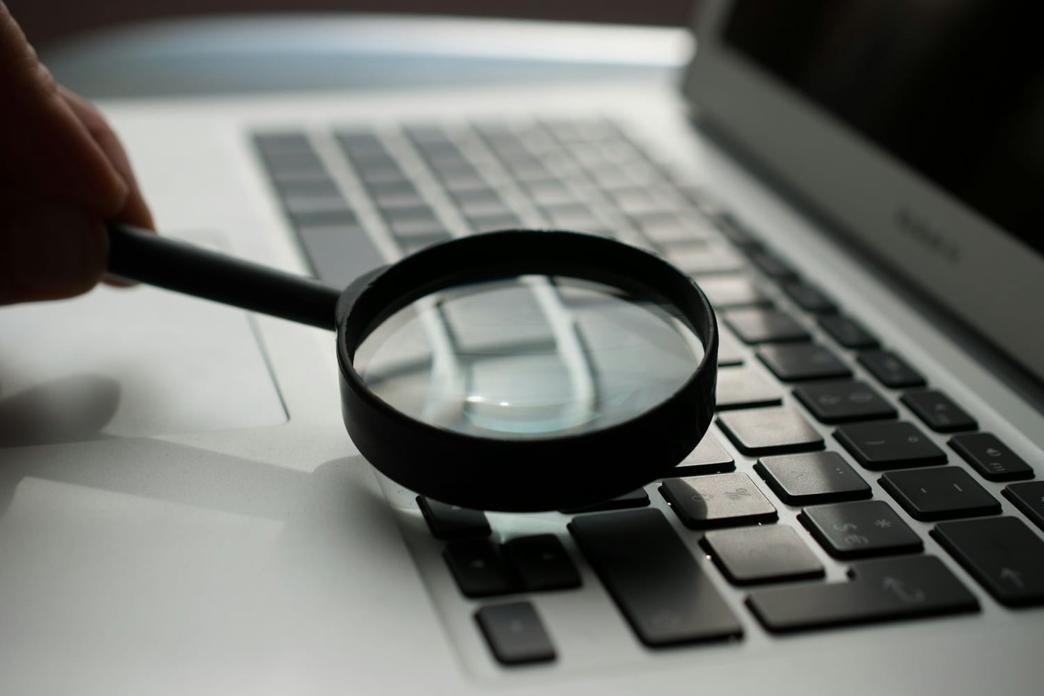 A magnifying glass held over a laptop keyboard